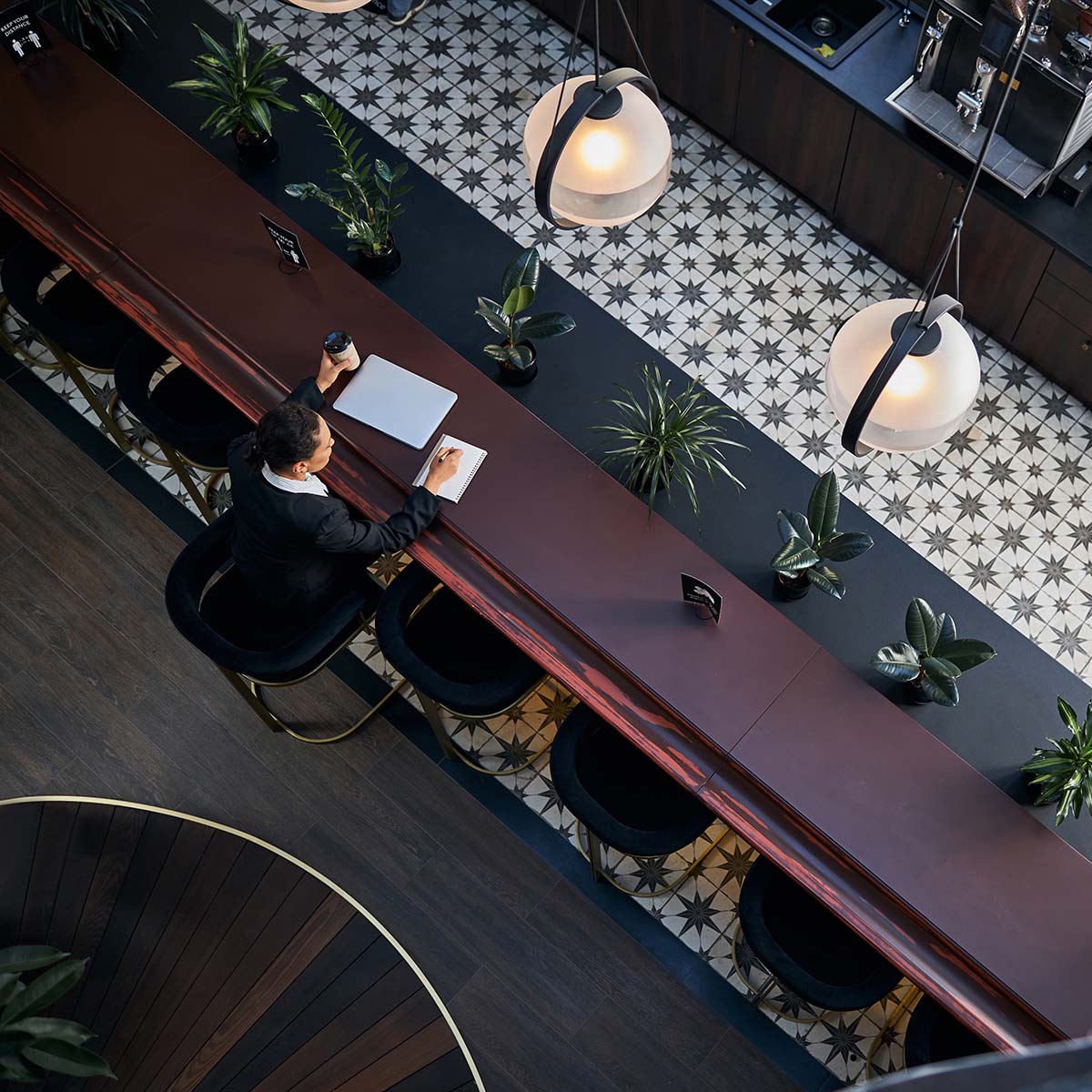 Concentrated businesslady sitting at the table while making notes and drinking coffee